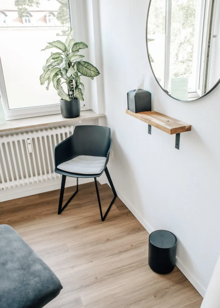 Sitzecke am Fenster mit Pflanze, Stuhl und rundem Spiegel